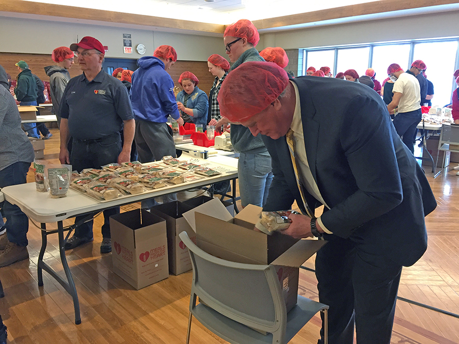 Chancellor Bob Meyer puts filled meal packets into boxes and says he is proud of the volunteers.
