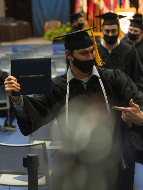 A graduate celebrates receiving his diploma after years of hard work.